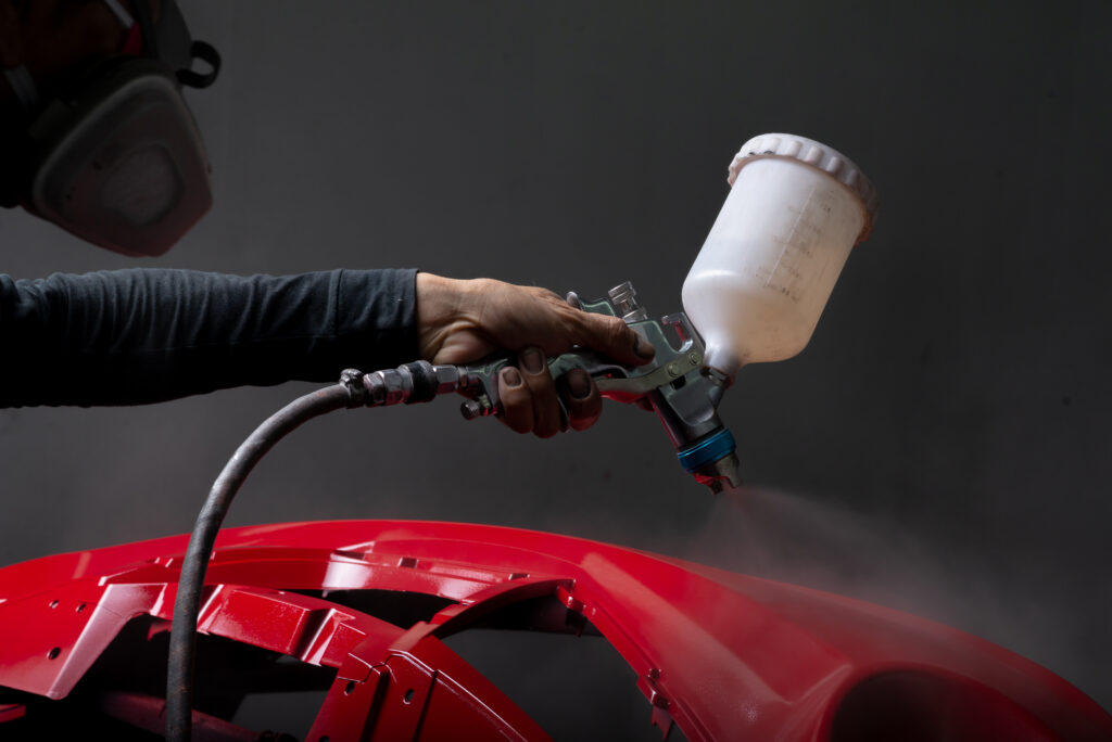 Red Bumper Being Painted In Paint Booth