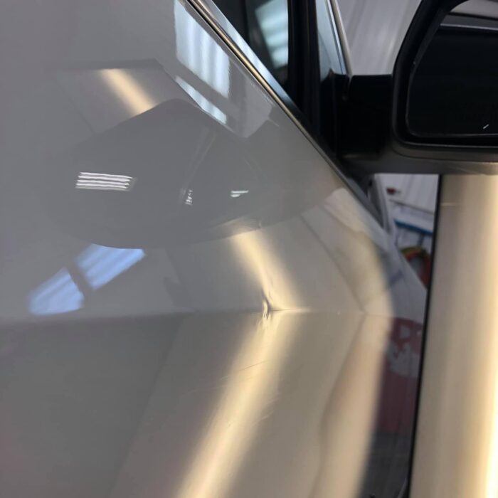 Before picture of paintless dent repair on a white SUV