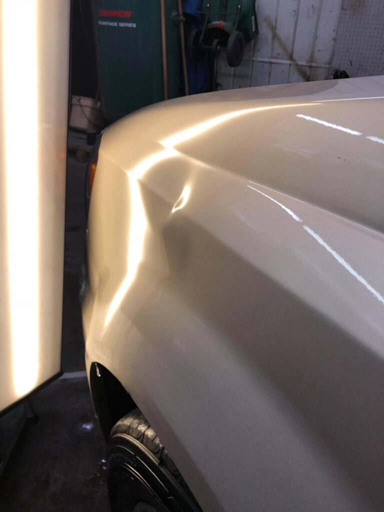 Before picture of paintless dent repair on a white truck