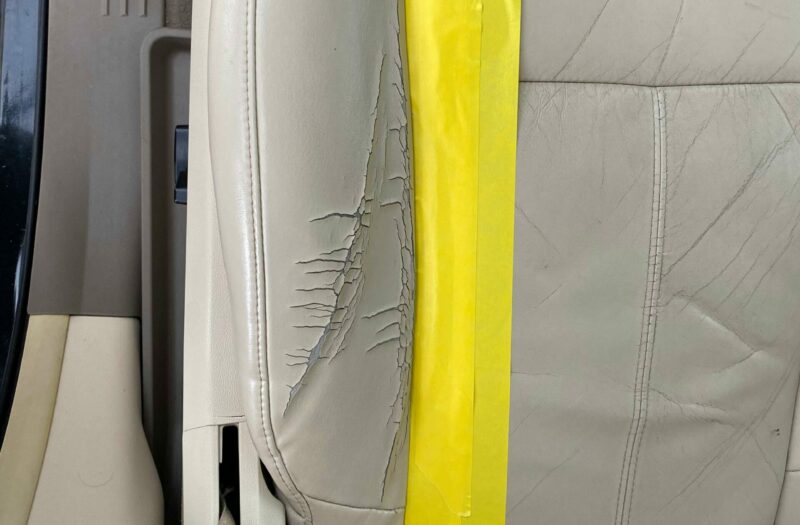 ripped grey upholstry with yellow tape to cover damage